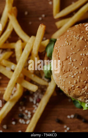 Vista superiore della deliziosa burger con sesamo sul panino e patatine fritte con sale Foto Stock