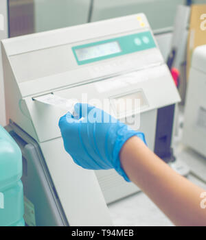 La donna lavora in un laboratorio su una moderna macchina per prove del sangue. Medico controlla il sangue dei pazienti. La ricerca di sangue in un moderno wo scientifica Foto Stock