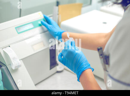 La donna lavora in un laboratorio su una moderna macchina per prove del sangue. Medico controlla il sangue dei pazienti. La ricerca di sangue in un moderno wo scientifica Foto Stock