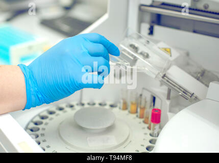 La donna lavora in un laboratorio su una moderna macchina per prove del sangue. Medico controlla il sangue dei pazienti. La ricerca di sangue in un moderno wo scientifica Foto Stock