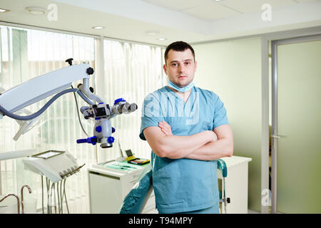 Un maschio di dentista è in piedi con un microscopio Foto Stock