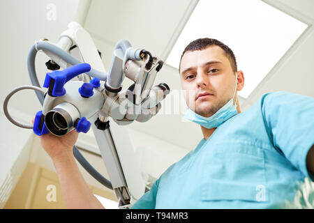 Un maschio di dentista è in piedi con un microscopio Foto Stock