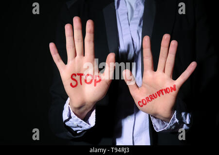 Donna con testo STOP ALLA CORRUZIONE scritto sui suoi palmi delle mani contro lo sfondo nero, primo piano Foto Stock