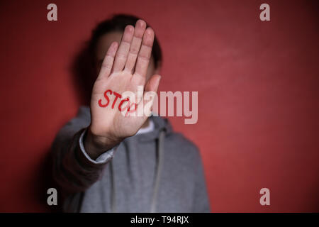 Donna con la parola STOP scritto sul suo palmo contro il colore di sfondo. Concetto di corruzione Foto Stock
