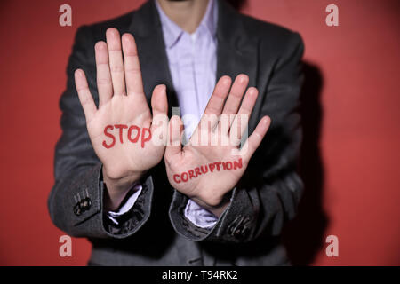 Donna con testo STOP ALLA CORRUZIONE scritto sul suo palms contro il colore di sfondo Foto Stock