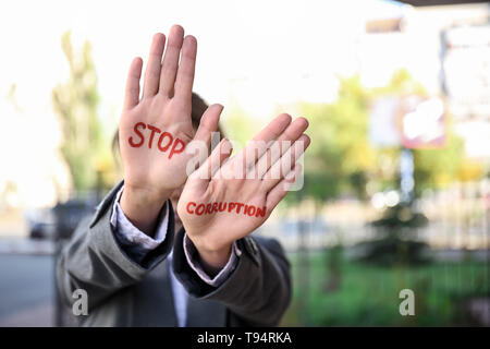 Donna con testo STOP ALLA CORRUZIONE scritto sui suoi palmi all'aperto Foto Stock