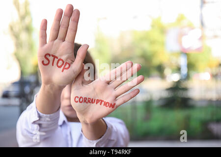 Donna con testo STOP ALLA CORRUZIONE scritto sui suoi palmi all'aperto Foto Stock