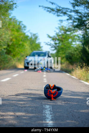 Close-up di un ciclismo casco caduto su asfalto accanto a una bicicletta dopo l incidente di auto sulla strada Foto Stock