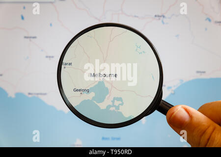 Melbourne, Australia. Mappa politico. La città sullo schermo del monitor attraverso una lente di ingrandimento in mano. Foto Stock