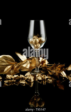 Wineglass con oro di noci e noccioline su sfondo scuro Foto Stock