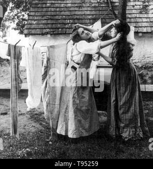 Titolo: "problemi sulla linea' mostra due donne tirando ogni altri i capelli davanti di stendibiancheria. Stereografia ritagliata fotografata da E.W. Kelley, 1906. Foto Stock