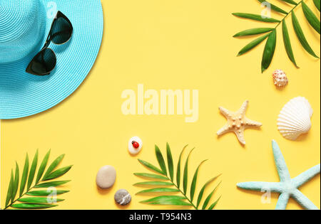 Sfondo tropicale. Palme rami, hat con stella marina e conchiglia su sfondo giallo. Il viaggio. Spazio di copia Foto Stock