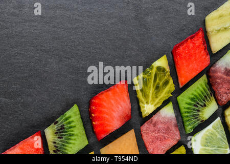 Composizione astratta della forma a diamante di frutta vari puzzle di pietra nera con uno sfondo con spazio di copia Foto Stock