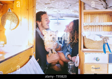 Coppia felice divertendosi in minivan vintage con il loro cane durante un viaggio su strada - Giovani godendo del tempo insieme e ridere in vacanza vacanze Foto Stock