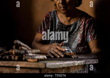 Laura Peña, un 67-anno-vecchia donna di El Salvador, rotoli di foglie di tabacco per fare sigari fatti a mano nella sua casa di Suchitoto, El Salvador. Foto Stock