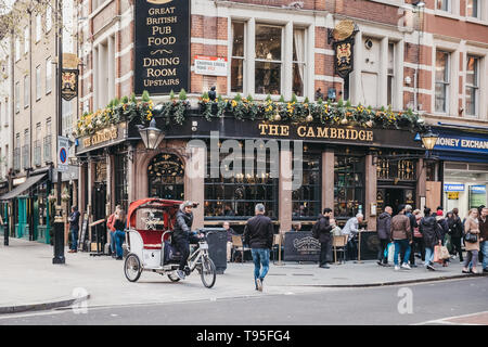 London, Regno Unito - 13 Aprile 2019: Rickshaw su una strada di fronte al Cambridge, un tradizionale pub di carattere unico accanto al Palazzo del Teatro su Chari Foto Stock