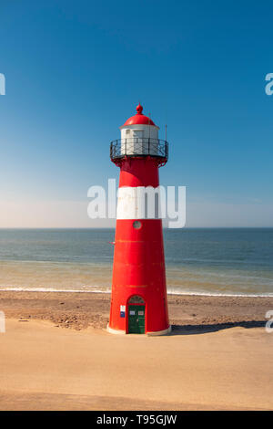 Un rosso e bianco faro di mare sotto un cielo azzurro vicino a Westkapelle in Zeeland, Paesi Bassi. Foto Stock