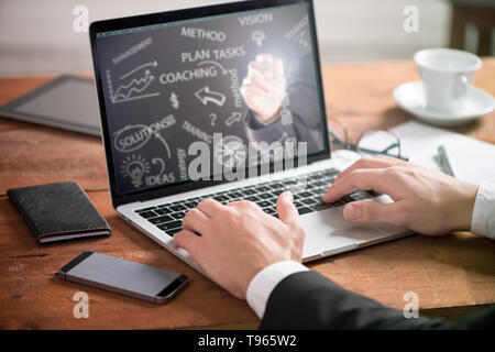 Aziendali di man mano sul tavolo utilizzando un computer portatile con un Responsabile di progetto di ricerca di processo Foto Stock