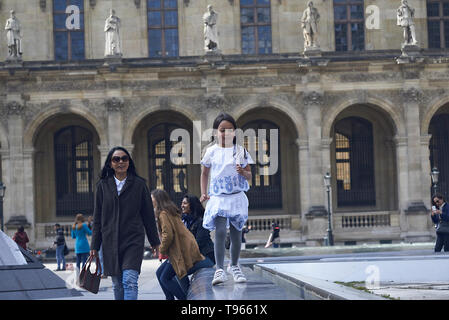 Donna asiatica e sua figlia di fronte al Museo del Louvre nel centro della città di Parigi nel sole primaverile Foto Stock