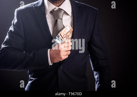 Imprenditore mettendo il denaro in tasca, uomo elegante suite e legare con le banconote in euro da vicino Foto Stock