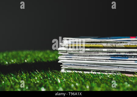 Pila di stampa diversi quotidiani su fresco verde erba isolato su nero Foto Stock