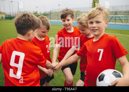 I bambini sul Calcio Calcio team mettendo le mani a. Ragazzi Scuola Calcio team Huddling. I bambini le mani insieme in un Huddle Foto Stock