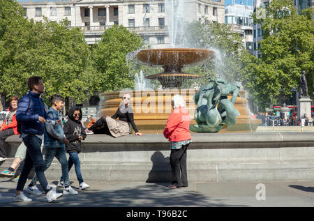 Turisti e londinesi godendo una giornata fuori e rilassarsi su Trafalgar Square, London, Regno Unito in un caldo pomeriggio di sole in maggio. Foto Stock