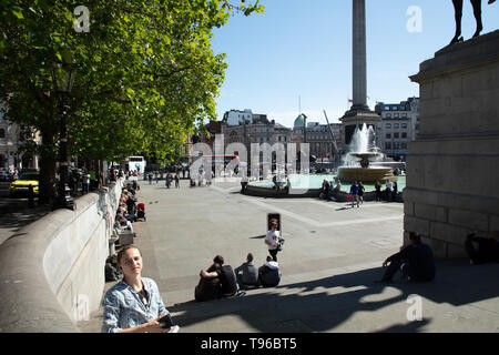 Turisti e londinesi godendo una giornata fuori e rilassarsi su Trafalgar Square, London, Regno Unito in un caldo pomeriggio di sole in maggio. Foto Stock