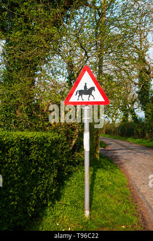 Il traffico su strada cartello di avviso per avvertire gli automobilisti a diffidare di cavalli e cavalieri in avanti intorno all'angolo più probabilità di essere visto nel paesaggio rurale Foto Stock