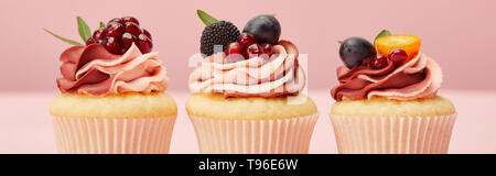 Panoramica del dolce tortine con bacche e frutti sulla superficie rosa Foto Stock