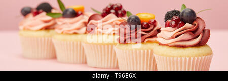 Panoramica del dolce tortine con bacche e frutti sulla superficie rosa Foto Stock