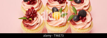 Panoramica del dolce tortine con bacche e frutti sulla superficie rosa Foto Stock