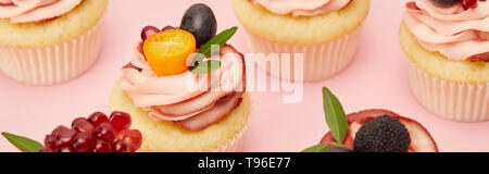 Panoramica del dolce tortine con bacche e frutti sulla superficie rosa Foto Stock