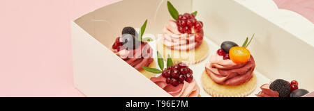 Panoramica delle tortine con frutti di bosco e frutta in scatola di cartone isolati su rosa Foto Stock