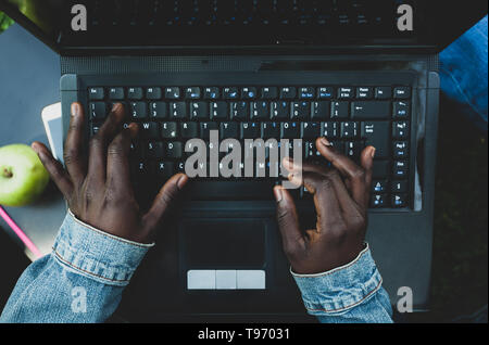 Chiudere fino a mani di una giovane donna africana la digitazione sulla tastiera del notebook. Foto Stock