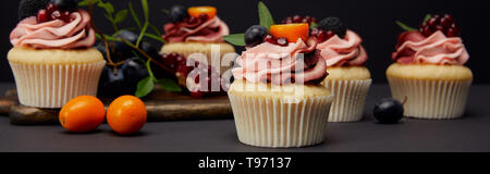 Panoramica delle tortine con crema di latte e frutta e bacche isolato su nero Foto Stock