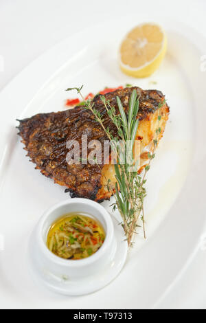 La Passera di mare alla griglia con limone, erbe e salsa appetitosa sulla piastra bianca Foto Stock