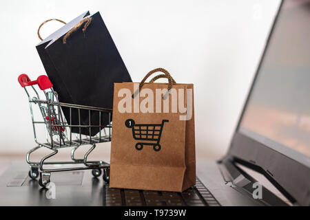 La carta delle borse per lo shopping e il carrello sul computer portatile. Shopping online e di e-commerce concept Foto Stock