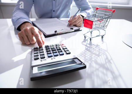 Close-up di uomo calcolare le spese per lo shopping vicino al Carrello della Spesa Foto Stock