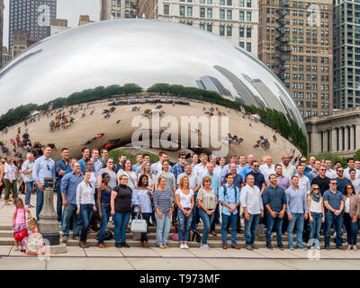 I turisti posano per una foto di gruppo a Cloud Gate al Millenium Park di Chicago. Il Cloud Gate è un pubblico scultura di Indiano-nato artista britannico Sir Anish Kapoor, che è il fulcro della AT&T Plaza al Millennium Park nel Loop area comunitaria. Foto Stock