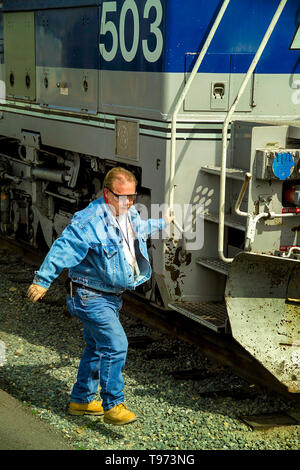 Dopo essere arrivati a Los Angeles cantiere ferroviario, un treno ingegnere indossare occhiali di sicurezza e stivali si arrampica verso il basso la scaletta del suo locomotore. Foto Stock