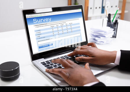 Close-up di una imprenditrice della mano in linea di riempimento il modulo del sondaggio sul computer portatile in ufficio Foto Stock