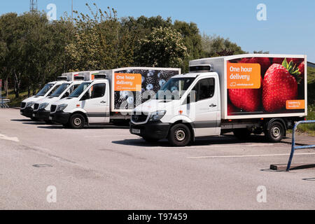 Una linea di quattro Sainsburys Home furgoni parcheggiati in negozio di parcheggio auto. Foto Stock