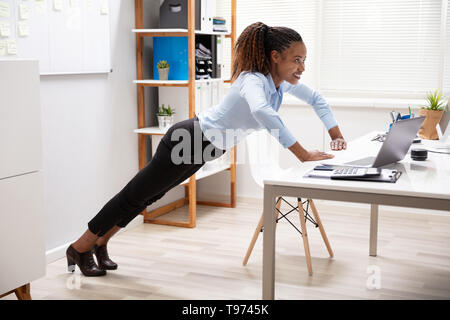 Vista laterale di un felice giovane imprenditrice facendo spingere fino al luogo di lavoro Foto Stock