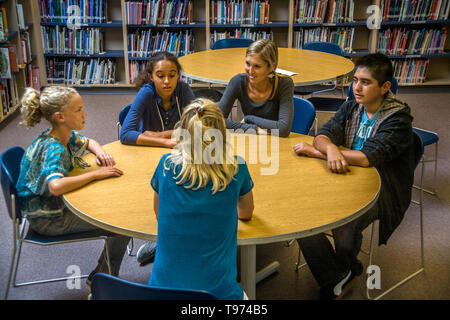 Un junior high school consigliere risponde con un gruppo multietnico di studenti in una San Clemente, CA, biblioteca scolastica. Foto Stock