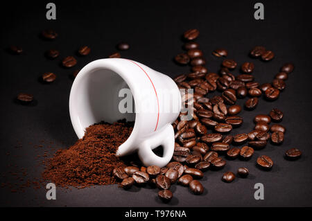 Cup con mucchio di chicchi di caffè su sfondo nero Foto Stock