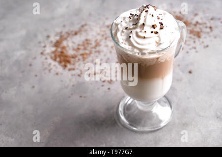 Bicchiere di caffè freddo coperto con panna montata sulla tabella grigia Foto Stock