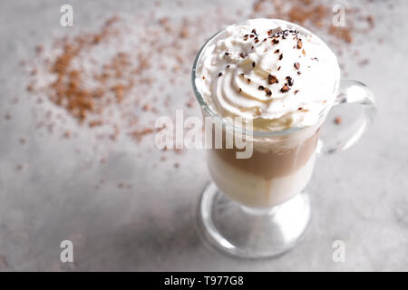 Bicchiere di caffè freddo coperto con panna montata sulla tabella grigia Foto Stock