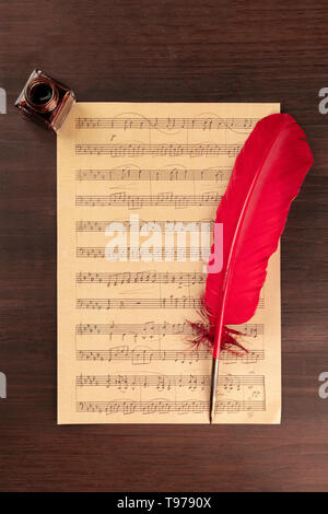 Un pezzo di musica del foglio, ripresa dall'alto su una scuri in legno rustico sfondo con una penna del cappello e un inchiostro ben Foto Stock