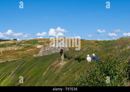 La Normandia, Francia - 25 agosto 2018: Coppia di anziani turisti vicino a resti di un antica chiesa della Cape Carteret. Barneville-Carteret, Normandia, Francia Foto Stock